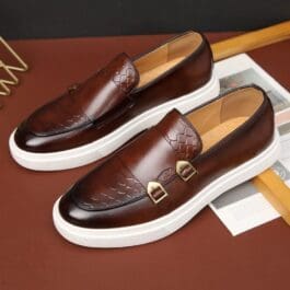 A pair of brown Men's Casual Leather Shoes with buckles on a dark background.