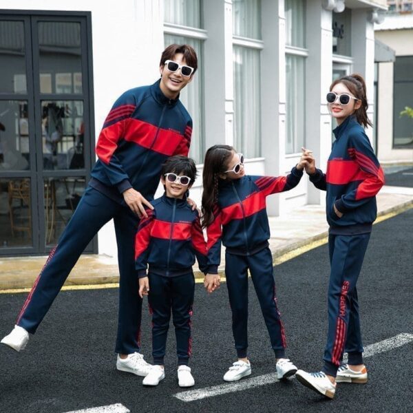 Matching parent-child sports suits featuring two adults and two children wearing coordinated red and navy tracksuits, posing together outdoors, showcasing a family-friendly athletic fashion style.