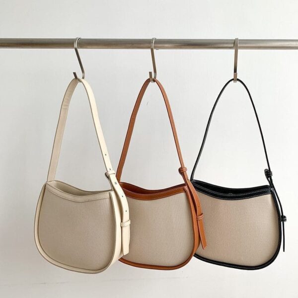 Three canvas versatile bucket shoulder bags hang in a row from a metal rod against a neutral background.