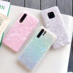 Three Shell Phone Cases for Huawei displayed on a white surface, featuring pastel pink, blue, and purple colors with a glittery texture that adds a stylish and protective accessory option for Huawei smartphone users.