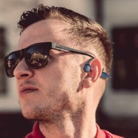 A man in sunglasses and a red shirt, showcasing a Bone Conduction Bluetooth Headset for a modern, stylish look.