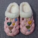 A pair of pink cotton slippers adorned with heart patterns, designed for warmth and non-slip comfort.