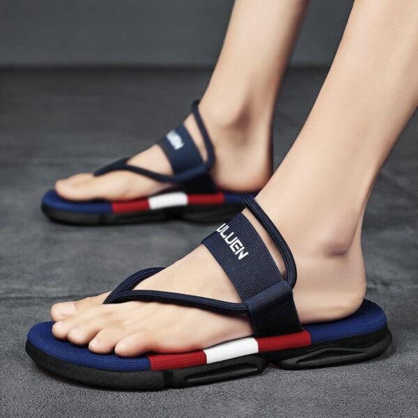 A pair of feet wearing modern navy-blue and red Outdoor Sport Sandals on a grey surface.