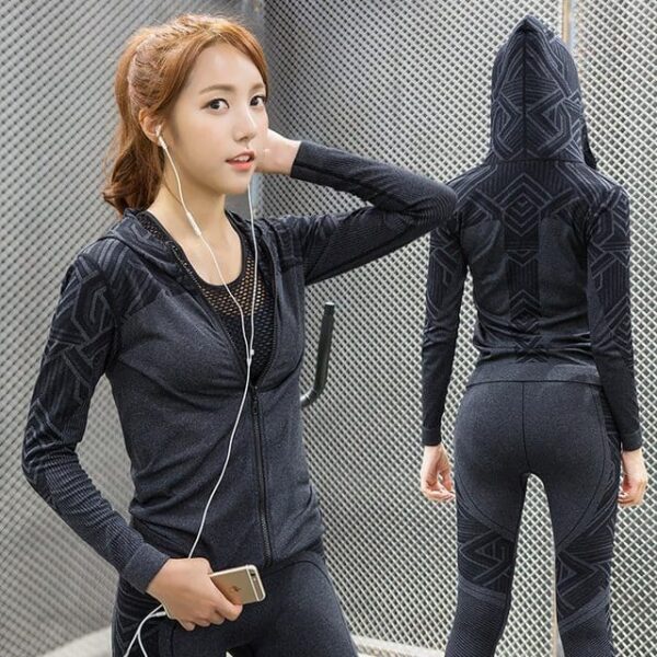 woman wearing a black aRunning yoga fitness apparel. She is wearing a long-sleeved, zip-up jacket with a mesh insert on the back.