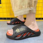 A person wearing black and orange sandals, showcasing men's casual outdoor sports platform slippers.