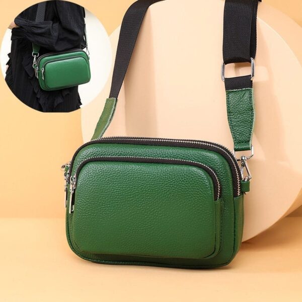 The Trendy Multi-layer Leather Handbag is a striking green color, compact in a rectangular shape with rounded edges. Its textured surface suggests high-quality leather, and silver-toned hardware adds a modern touch. Multiple compartments are visible, indicated by zippers that blend functionality with style. Against a soft beige background, the vibrant hue stands out. An additional strap in the top left corner suggests versatile carrying options.