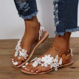 Boho beach sandals adorned with white flowers, perfect for a stylish summer look and comfortable beach outings.