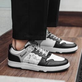 Person wearing black and white Casual Ink Painting Sneakers with cropped trousers standing on a wooden floor.