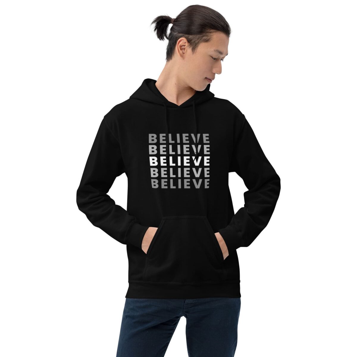 Wearing the Fashionable Unisex Hoodie - Trendy and Comfortable for All, a person sports a black hoodie with BELIEVE printed in gray and white shades, hands tucked in pockets, exuding a stylish and contemplative vibe.