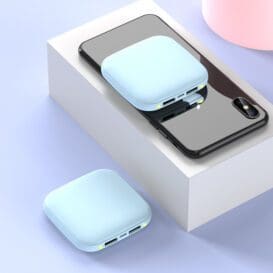 Compact Mini power bank 20000mAh in light blue color, charging a smartphone placed on a white surface, with an additional power bank unit lying beside it.