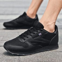 Black lightweight running shoes on person’s feet, showcasing sleek design and comfort for active lifestyle.