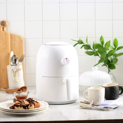 Modern kitchen with white air fryer, wooden cutting board, and green plant enhancing dining and bar experience.