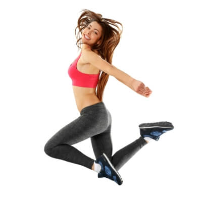 Woman in sportswear jumping energetically against a white background, showcasing comfortable and stylish fitness attire.