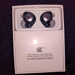 A pair of black KZ earbuds in a white box